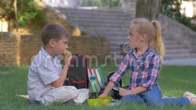 学生们在课间午餐时聊天，手里拿着三明治坐在校园的草地上